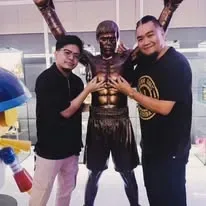 Dos expositores de la feria de creadores posando junto a una escultura de cuerpo entero